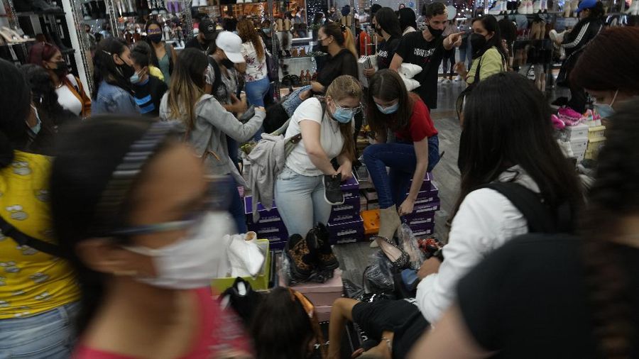 Shoppers, wearing protective face masks, line up to enter the Sambil Mall, in Caracas, Venezuela, Friday, Nov. 26, 2021.  At malls and few stores, Venezuelans are taking the opportunity to buy clothes and other articles with generous Black Friday discounts. (AP Photo/Ariana Cubillos)