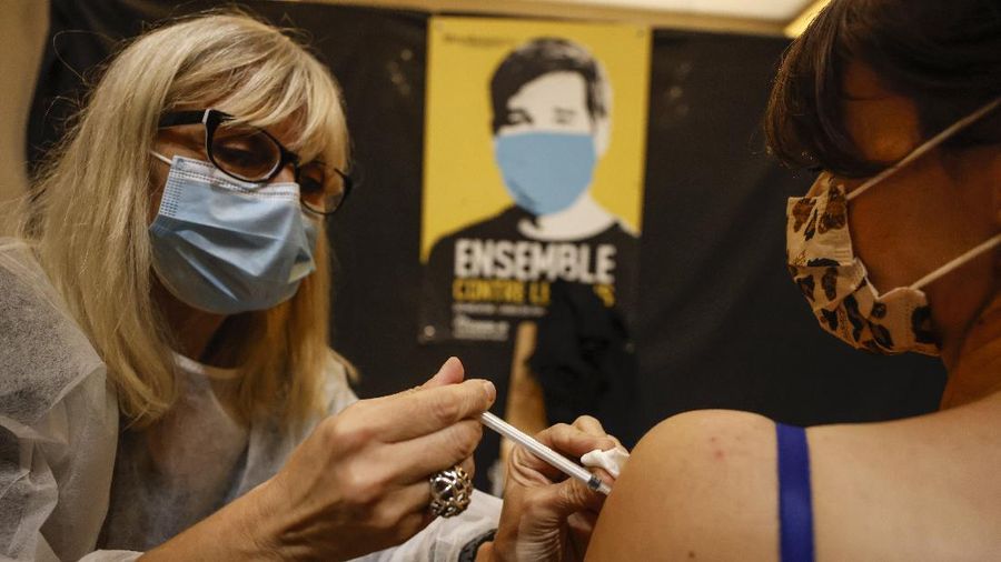 A woman receives Pfizer COVID-19 vaccines by medical staff at Christmas market in Strasbourg, eastern France, Friday, Nov. 26, 2021. France has launched a plan to give COVID-19 booster shots to all adults, as it opted against a further lockdown or curfew to help combat a worrying uptick in infections in the country at Christmas season. (AP Photo/Jean-Francois Badias)