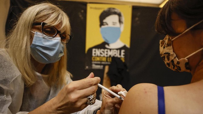 A woman receives Pfizer COVID-19 vaccines by medical staff at Christmas market in Strasbourg, eastern France, Friday, Nov. 26, 2021. France has launched a plan to give COVID-19 booster shots to all adults, as it opted against a further lockdown or curfew to help combat a worrying uptick in infections in the country at Christmas season. (AP Photo/Jean-Francois Badias)