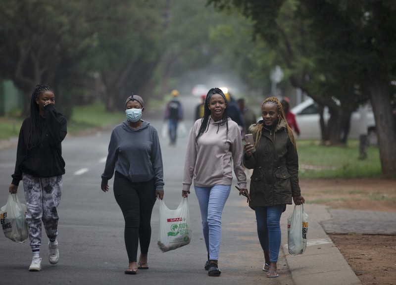 A petrol attendant stands next to a newspaper headline in Pretoria, South Africa, Saturday, Nov. 27, 2021. As the world grapples with the emergence of the new variant of COVID-19, scientists in South Africa — where omicron was first identified — are scrambling to combat its spread across the country. (AP Photo/Denis Farrell)