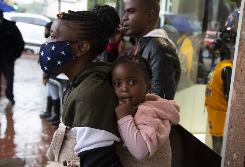 A petrol attendant stands next to a newspaper headline in Pretoria, South Africa, Saturday, Nov. 27, 2021. As the world grapples with the emergence of the new variant of COVID-19, scientists in South Africa — where omicron was first identified — are scrambling to combat its spread across the country. (AP Photo/Denis Farrell)