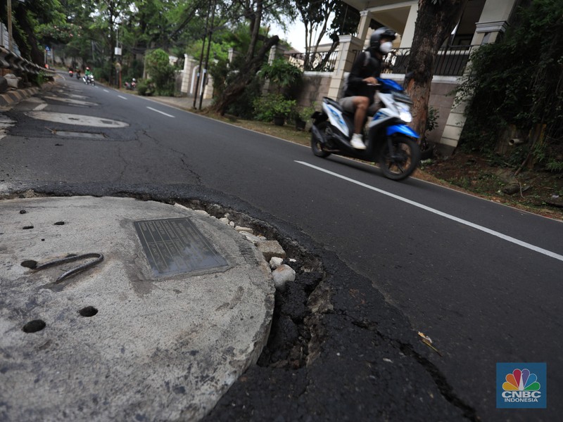 Pengendara motor melintas di samping galian proyek sumur resapan di jalan Lebak Bulus III, Jakarta, Selasa, (30/11/2021). (CNBC Indonesia/Muhammad Sabki)