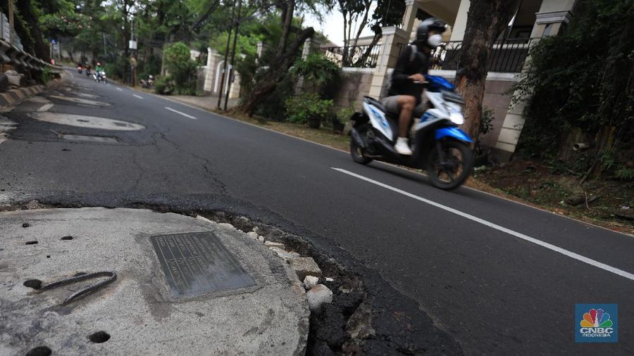 Pengendara motor melintas di samping galian proyek sumur resapan di jalan Lebak Bulus III, Jakarta, Selasa, (30/11/2021). (CNBC Indonesia/Muhammad Sabki)