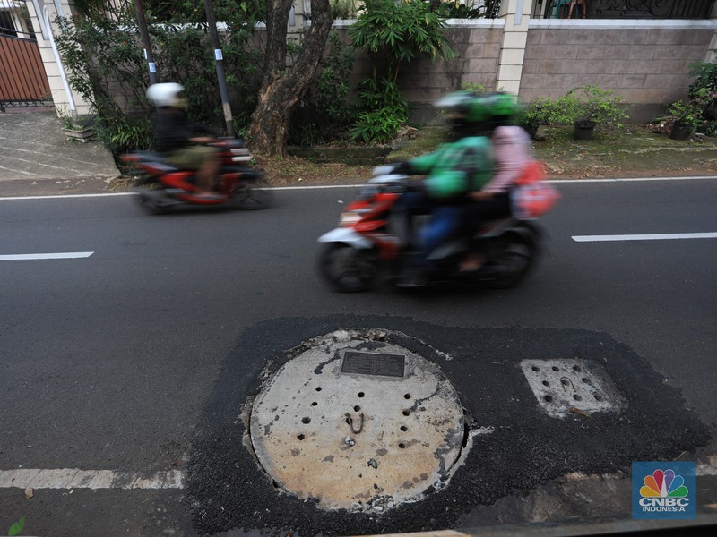 Pengendara motor melintas di samping galian proyek sumur resapan di jalan Lebak Bulus III, Jakarta, Selasa, (30/11/2021). (CNBC Indonesia/Muhammad Sabki)