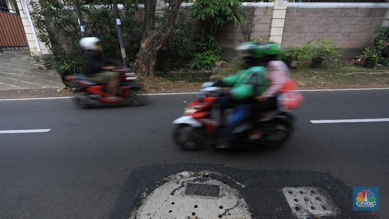 Pengendara motor melintas di samping galian proyek sumur resapan di jalan Lebak Bulus III, Jakarta, Selasa, (30/11/2021). (CNBC Indonesia/Muhammad Sabki)