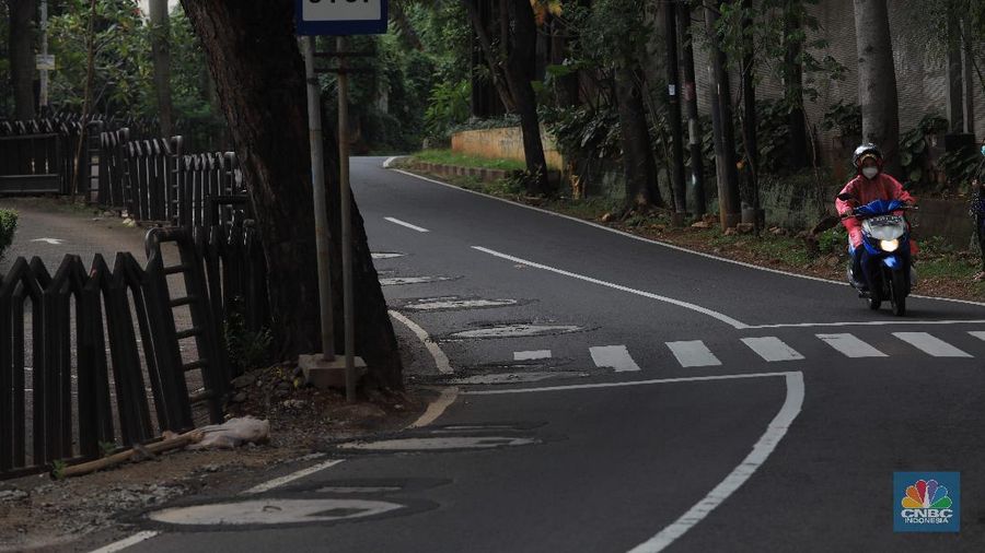 Pengendara motor melintas di samping galian proyek sumur resapan di jalan Lebak Bulus III, Jakarta, Selasa, (30/11/2021). (CNBC Indonesia/Muhammad Sabki)