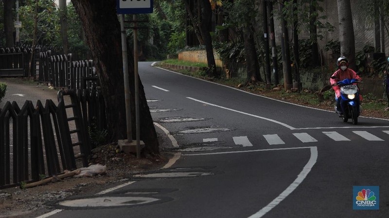 Pengendara motor melintas di samping galian proyek sumur resapan di jalan Lebak Bulus III, Jakarta, Selasa, (30/11/2021). (CNBC Indonesia/Muhammad Sabki)