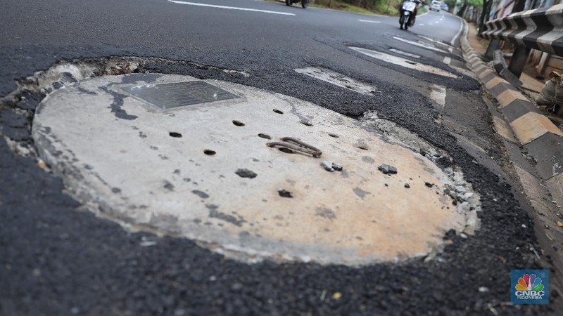 Pengendara motor melintas di samping galian proyek sumur resapan di jalan Lebak Bulus III, Jakarta, Selasa, (30/11/2021). (CNBC Indonesia/Muhammad Sabki)