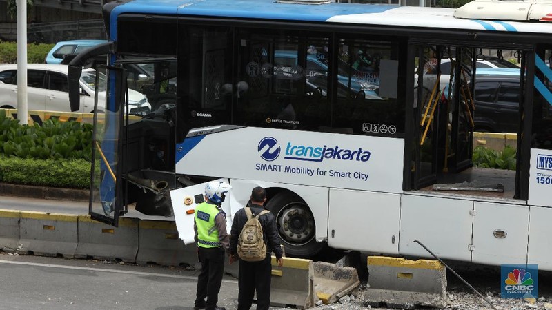 Petugas melihat kondisi bus Transjakarta yang mengalami kecelakaan di depan Ratu Plaza, Jakarta, Jumat (3/12/2021). (CNBC Indonesia/Andrean Kristianto)