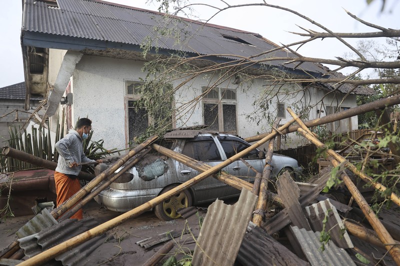 A man brings his buffaloes for evacuation past houses covered with ash following an eruption of Mount Semeru, seen in the background, in Lumajang, East Java, Indonesia, Sunday, Dec. 5, 2021. The highest volcano on Indonesia’s most densely populated island of Java spewed thick columns of ash, searing gas and lava down its slopes in a sudden eruption triggered by heavy rains on Saturday. (AP Photo/Trisnadi)