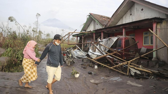 Kondisi Rumah Warga Usai Erupsi Gunung Semeru (5/12/2021) Villagers walk near their damaged home in an area affected by the eruption of Mount Semeru in Lumajang, East Java, Indonesia, Sunday, Dec. 5, 2021. The highest volcano on Indonesia’s most densely populated island of Java spewed thick columns of ash, searing gas and lava down its slopes in a sudden eruption triggered by heavy rains on Saturday. (AP Photo/Trisnadi)