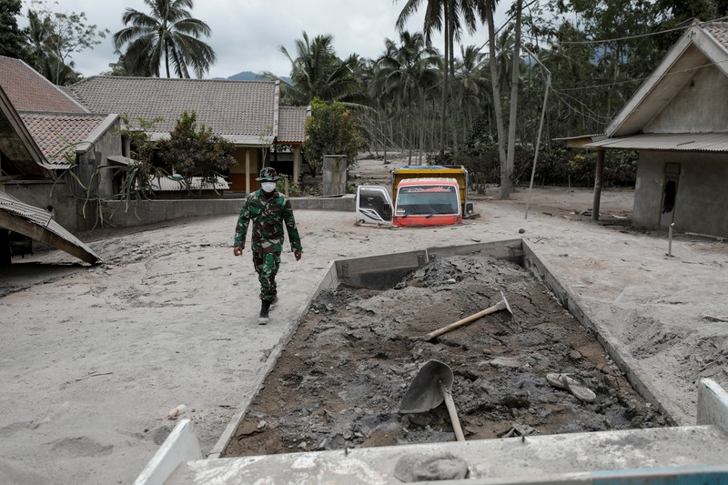 Kondisi Rumah Warga Usai Erupsi Gunung Semeru (5/12/2021) An Indonesian soldier walks past damage trucks at Sumberwuluh village following the eruption of Semeru mount volcano in Lumajang regency, East Java province, Indonesia, December 5, 2021. REUTERS/Willy Kurniawan
