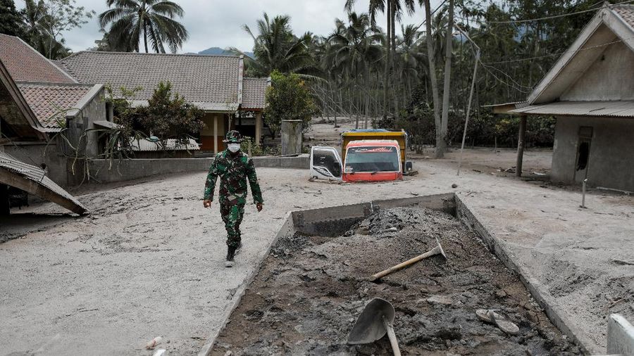 An Indonesian soldier walks past damage trucks at Sumberwuluh village following the eruption of Semeru mount volcano in Lumajang regency, East Java province, Indonesia, December 5, 2021. REUTERS/Willy Kurniawan
