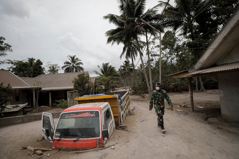 Kondisi Rumah Warga Usai Erupsi Gunung Semeru (5/12/2021) An Indonesian soldier walks past damage trucks at Sumberwuluh village following the eruption of Semeru mount volcano in Lumajang regency, East Java province, Indonesia, December 5, 2021. REUTERS/Willy Kurniawan