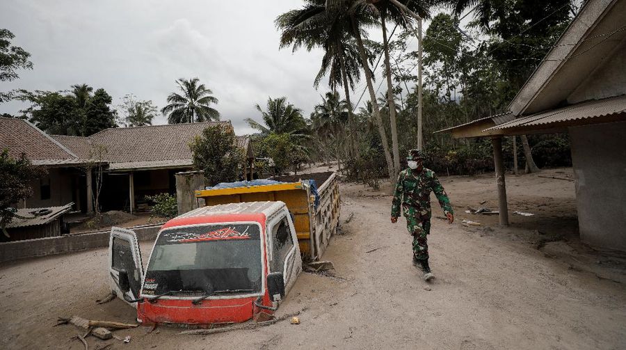 An Indonesian soldier walks past damage trucks at Sumberwuluh village following the eruption of Semeru mount volcano in Lumajang regency, East Java province, Indonesia, December 5, 2021. REUTERS/Willy Kurniawan