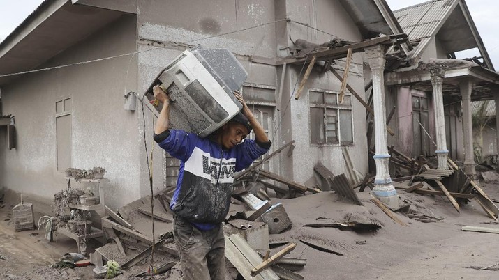 Indonesia Volcano A man carries a television as he evacuates to a safer place following the eruption of Mount Semeru in Lumajang district, East Java province, Indonesia, Monday, Dec. 6, 2021. The highest volcano on Java island spewed thick columns of ash into the sky in a sudden eruption Saturday triggered by heavy rains. Villages and nearby towns were blanketed and several hamlets buried under tons of mud from volcanic debris. (AP Photo/Trisnadi)