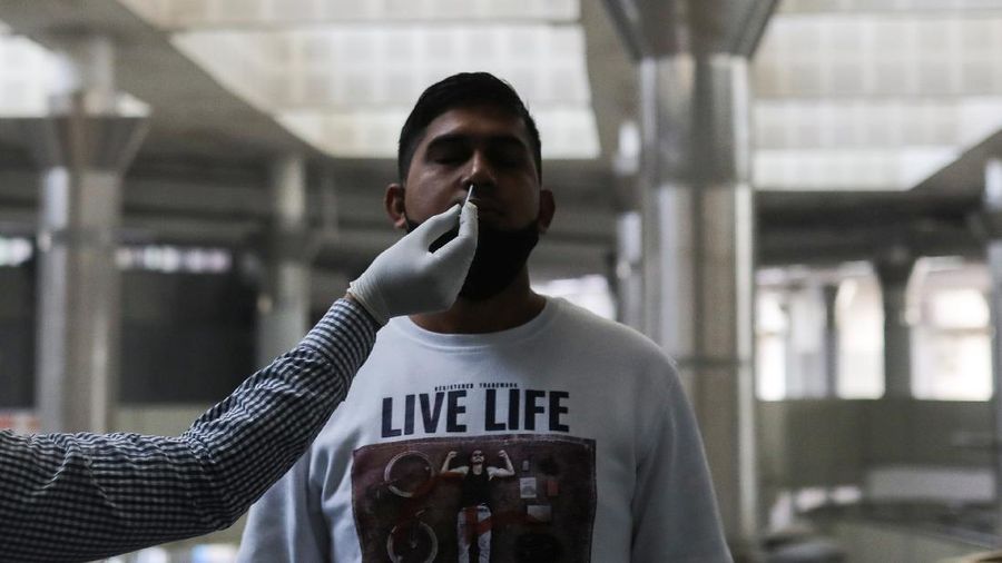 A healthcare worker collects a coronavirus disease (COVID-19) test swab sample from a man at a bus terminal in New Delhi, India, December 6, 2021. REUTERS/Anushree Fadnavis