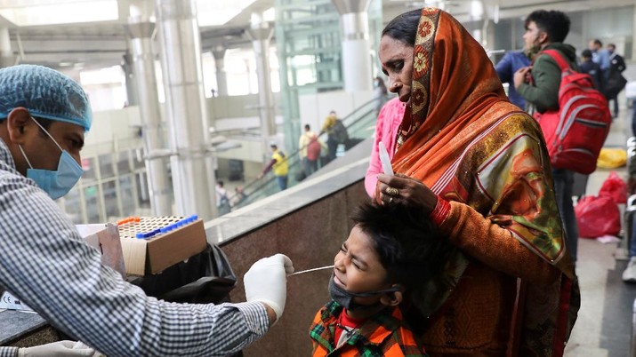 A healthcare worker collects a coronavirus disease (COVID-19) test swab sample from a boy at a bus terminal in New Delhi, India, December 6, 2021. REUTERS/Anushree Fadnavis