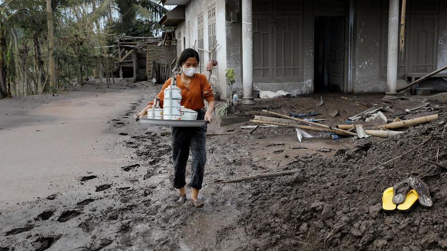 Disa Aprilia, 16, collects usable items from her house in an area affected by the eruption of Mount Semeru volcano, in Curah Roboan village, Pronojiwo district, in Lumajang, Indonesia, December 7, 2021. REUTERS/Willy Kurniawan