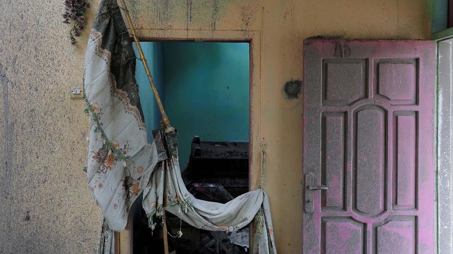Damaged curtains are seen alongside ash-covered walls and door in a house in an area affected by the eruption of Mount Semeru volcano in Curah Roboan village, Pronojiwo district, in Lumajang, Indonesia, December 7, 2021. REUTERS/Willy Kurniawan