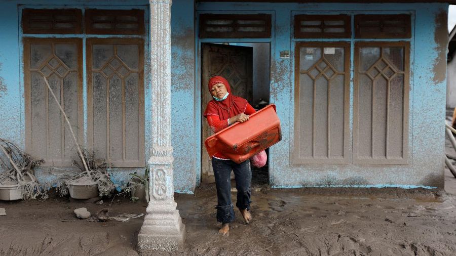 Locals transport a mattress on a motorcycle as Mount Semeru volcano continues to spew ash and smoke in the background following an eruption, in Gunung Sawur, Candipuro, Indonesia December 7, 2021. REUTERS/Willy Kurniawan     TPX IMAGES OF THE DAY