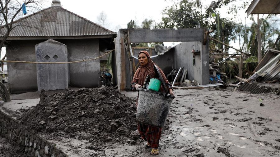 Locals transport a mattress on a motorcycle as Mount Semeru volcano continues to spew ash and smoke in the background following an eruption, in Gunung Sawur, Candipuro, Indonesia December 7, 2021. REUTERS/Willy Kurniawan     TPX IMAGES OF THE DAY