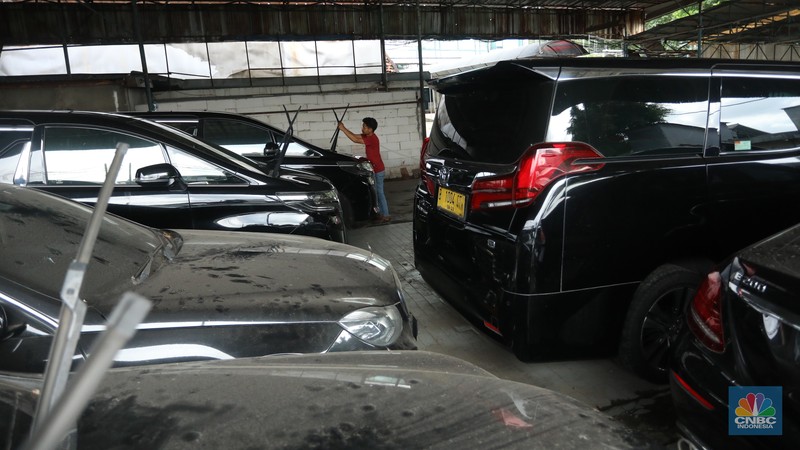 Pekerja merapihkan mobil eks-taksi yang akan dijual di showroom mobil Bluebird di kawasan Warung Buncit, Jakarta Selatan, Kamis (9/12/2021).  Mobil bekas armada taksi merupakan alternatif menarik bagi Anda yang berminat untuk mendapatkan kendaraan dengan harga lebih terjangkau. (CNBC Indonesia/Andrean Kristianto)