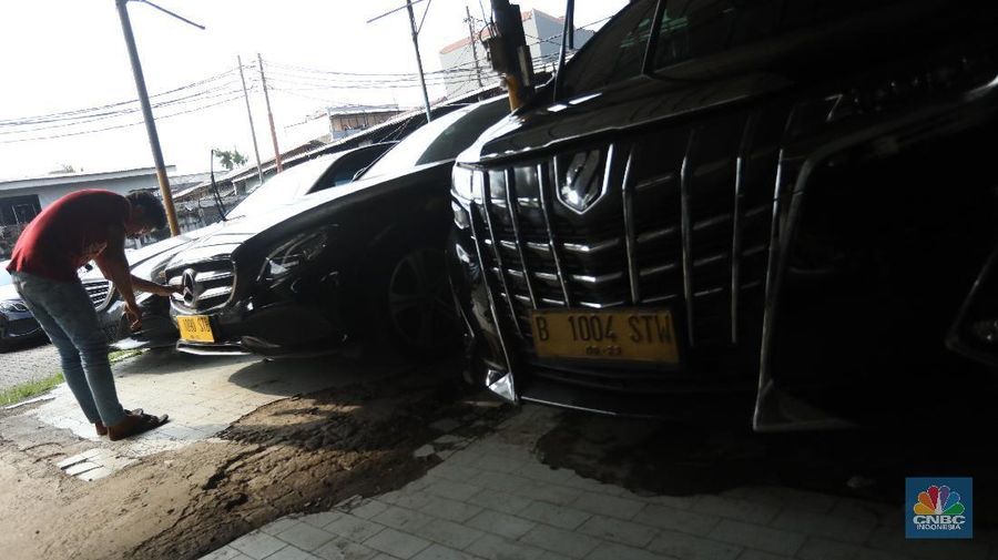 Pekerja merapihkan mobil eks-taksi yang akan dijual di showroom mobil Bluebird di kawasan Warung Buncit, Jakarta Selatan, Kamis (9/12/2021).  Mobil bekas armada taksi merupakan alternatif menarik bagi Anda yang berminat untuk mendapatkan kendaraan dengan harga lebih terjangkau. (CNBC Indonesia/Andrean Kristianto)