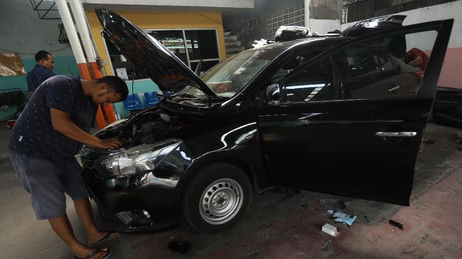 Pekerja merapihkan mobil eks-taksi yang akan dijual di showroom mobil Bluebird di kawasan Warung Buncit, Jakarta Selatan, Kamis (9/12/2021).  Mobil bekas armada taksi merupakan alternatif menarik bagi Anda yang berminat untuk mendapatkan kendaraan dengan harga lebih terjangkau. (CNBC Indonesia/Andrean Kristianto)