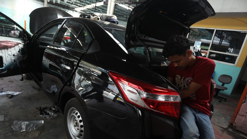 Pekerja merapihkan mobil eks-taksi yang akan dijual di showroom mobil Bluebird di kawasan Warung Buncit, Jakarta Selatan, Kamis (9/12/2021).  Mobil bekas armada taksi merupakan alternatif menarik bagi Anda yang berminat untuk mendapatkan kendaraan dengan harga lebih terjangkau. (CNBC Indonesia/Andrean Kristianto)