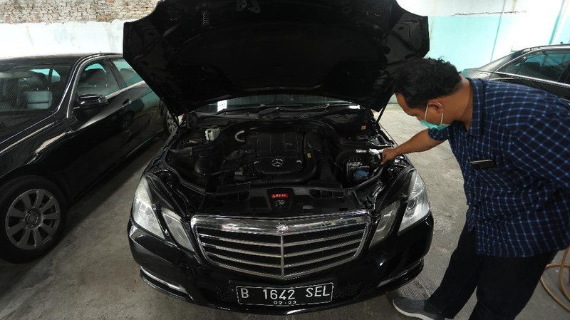 Pekerja merapihkan mobil eks-taksi yang akan dijual di showroom mobil Bluebird di kawasan Warung Buncit, Jakarta Selatan, Kamis (9/12/2021).  Mobil bekas armada taksi merupakan alternatif menarik bagi Anda yang berminat untuk mendapatkan kendaraan dengan harga lebih terjangkau. (CNBC Indonesia/Andrean Kristianto)
