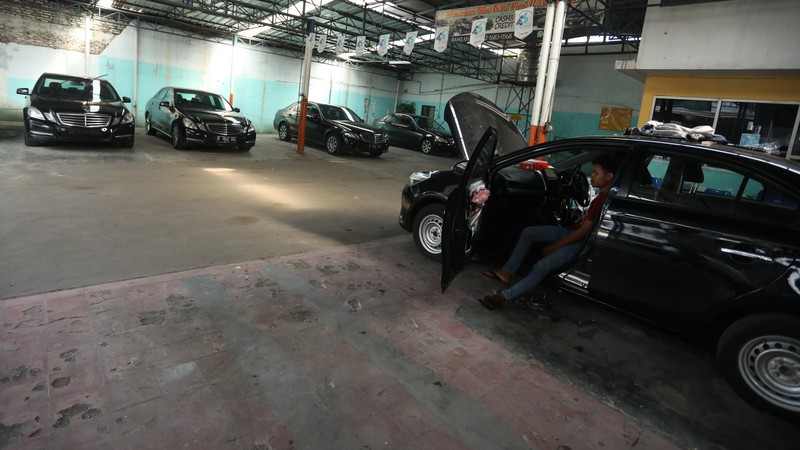 Pekerja merapihkan mobil eks-taksi yang akan dijual di showroom mobil Bluebird di kawasan Warung Buncit, Jakarta Selatan, Kamis (9/12/2021).  Mobil bekas armada taksi merupakan alternatif menarik bagi Anda yang berminat untuk mendapatkan kendaraan dengan harga lebih terjangkau. (CNBC Indonesia/Andrean Kristianto)