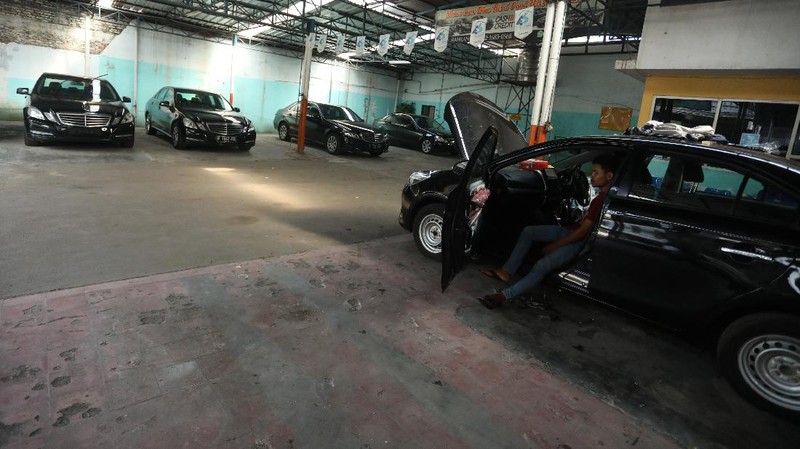 Pekerja merapihkan mobil eks-taksi yang akan dijual di showroom mobil Bluebird di kawasan Warung Buncit, Jakarta Selatan, Kamis (9/12/2021).  Mobil bekas armada taksi merupakan alternatif menarik bagi Anda yang berminat untuk mendapatkan kendaraan dengan harga lebih terjangkau. (CNBC Indonesia/Andrean Kristianto)