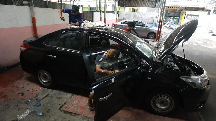 Pekerja merapihkan mobil eks-taksi yang akan dijual di showroom mobil Bluebird di kawasan Warung Buncit, Jakarta Selatan, Kamis (9/12/2021).  Mobil bekas armada taksi merupakan alternatif menarik bagi Anda yang berminat untuk mendapatkan kendaraan dengan harga lebih terjangkau. (CNBC Indonesia/Andrean Kristianto)
