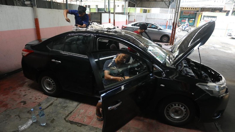 Pekerja merapihkan mobil eks-taksi yang akan dijual di showroom mobil Bluebird di kawasan Warung Buncit, Jakarta Selatan, Kamis (9/12/2021).  Mobil bekas armada taksi merupakan alternatif menarik bagi Anda yang berminat untuk mendapatkan kendaraan dengan harga lebih terjangkau. (CNBC Indonesia/Andrean Kristianto)