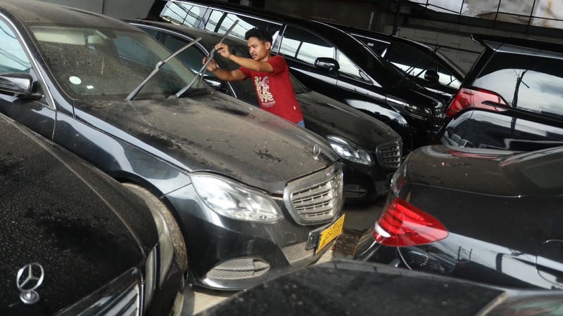 Pekerja merapihkan mobil eks-taksi yang akan dijual di showroom mobil Bluebird di kawasan Warung Buncit, Jakarta Selatan, Kamis (9/12/2021).  Mobil bekas armada taksi merupakan alternatif menarik bagi Anda yang berminat untuk mendapatkan kendaraan dengan harga lebih terjangkau. (CNBC Indonesia/Andrean Kristianto)