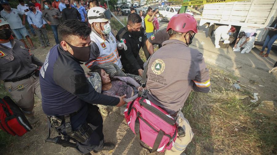 An injured migrant woman is moved by rescue personnel from the site of an accident near Tuxtla Gutierrez, Chiapas state, Mexico, Thursday, Dec. 9, 2021. Mexican authorities say at least 49 people were killed and dozens more injured when the truck carrying the migrants rolled over on the highway in southern Mexico. (AP Photo)