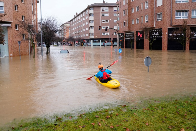 A man rides a kayak on a flooded road, following heavy rainfall in Pamplona, Spain, December 10, 2021. REUTERS/Vincent West