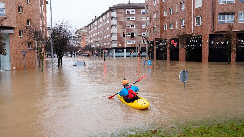 A man rides a kayak on a flooded road, following heavy rainfall in Pamplona, Spain, December 10, 2021. REUTERS/Vincent West