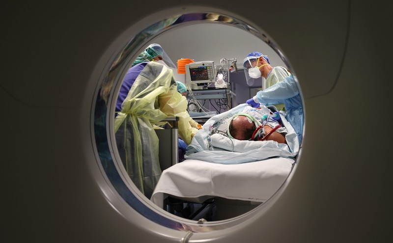 Medical staff transfer a patient in need of an ECMO (extracorporeal membrane oxygenation) life support unit for a CT examination at the coronavirus disease (COVID-19) Intensive Care Unit (ICU) of the 