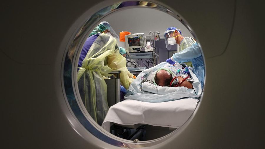 Medical staff transfer a patient in need of an ECMO (extracorporeal membrane oxygenation) life support unit for a CT examination at the coronavirus disease (COVID-19) Intensive Care Unit (ICU) of the 