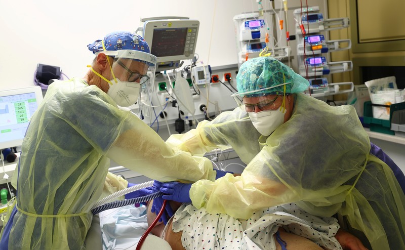 Perawatan Pasien Covid-19 di Jerman Medical staff transfer a patient in need of an ECMO (extracorporeal membrane oxygenation) life support unit for a CT examination at the coronavirus disease (COVID-19) Intensive Care Unit (ICU) of the