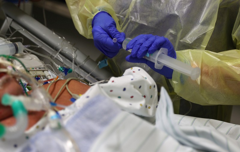 Medical staff transfer a patient in need of an ECMO (extracorporeal membrane oxygenation) life support unit for a CT examination at the coronavirus disease (COVID-19) Intensive Care Unit (ICU) of the 