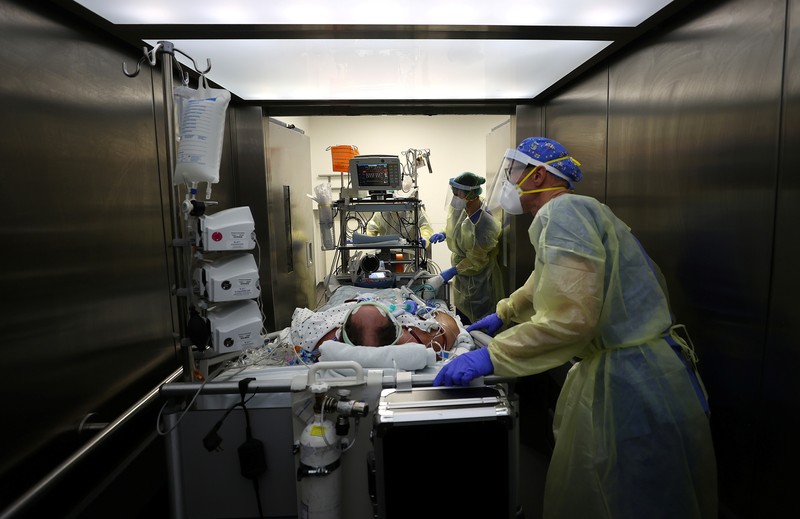Medical staff transfer a patient in need of an ECMO (extracorporeal membrane oxygenation) life support unit for a CT examination at the coronavirus disease (COVID-19) Intensive Care Unit (ICU) of the 
