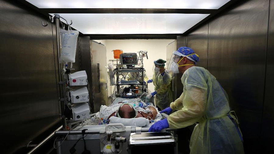 Medical staff transfer a patient in need of an ECMO (extracorporeal membrane oxygenation) life support unit for a CT examination at the coronavirus disease (COVID-19) Intensive Care Unit (ICU) of the 