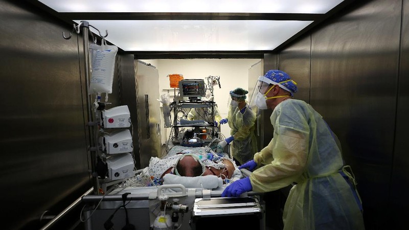 Medical staff transfer a patient in need of an ECMO (extracorporeal membrane oxygenation) life support unit for a CT examination at the coronavirus disease (COVID-19) Intensive Care Unit (ICU) of the 