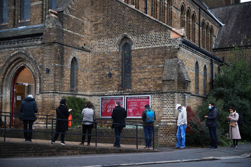 HEALTH-CORONAVIRUS/BRITAIN People queue outside a coronavirus disease (COVID-19) vaccination centre at a church in London, Britain, December 13, 2021. REUTERS/Hannah McKay