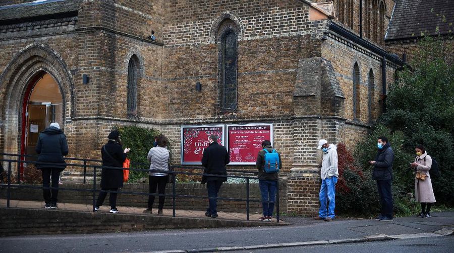 People queue outside a coronavirus disease (COVID-19) vaccination centre at a church in London, Britain, December 13, 2021. REUTERS/Hannah McKay