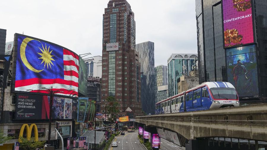 An LRT (Light Rain Transit) passes by a National flag signboard in Kuala Lumpur, Malaysia, Tuesday, Sept. 14, 2021. (AP Photo/Vincent Thian)