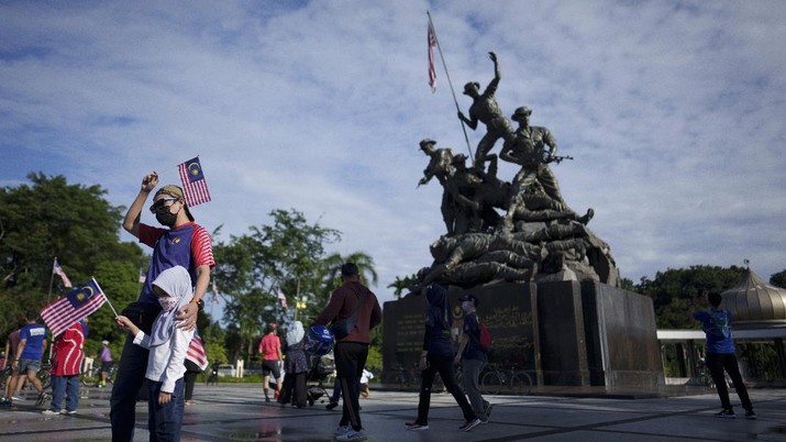 Malaysia National Day Visitors pose with Malaysian national flags for a photo in front of the National Monument during the 64th National Day celebrations to commemorate independence of Malaysia from British colonial rule, in Kuala Lumpur, Malaysia, Tuesday, Aug. 31, 2021. (AP Photo/Vincent Thian)